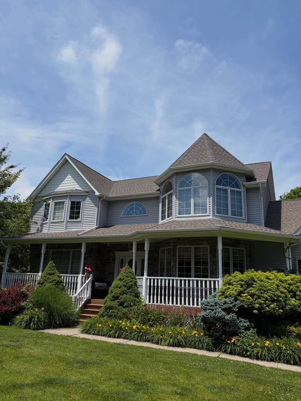 Blue Victorian with a wraparound porch after a full exterior wash