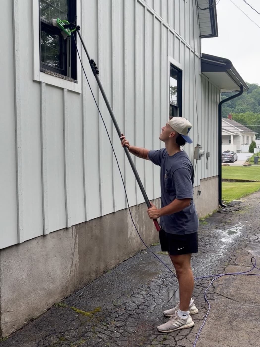 Anthony reaching second-story siding with a water-fed pole